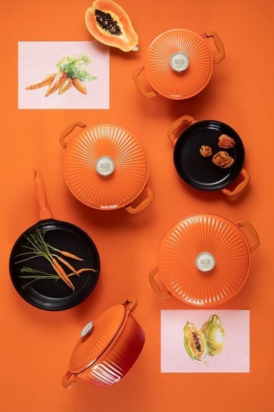 A top-down aesthetic product display featuring ceramic cookware set pieces arranged with fresh produce to evoke a fresh, culinary mood.