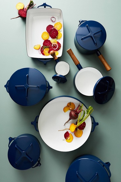 A high-angle, top-down shot of a navy blue enamel cookware set featuring vibrant sliced beets for a clean, minimalist, and premium aesthetic.