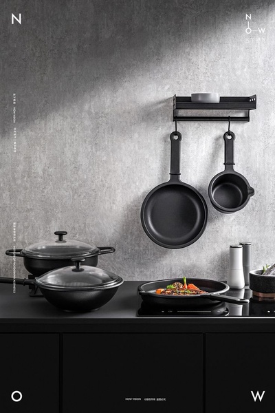 A high-end, monochromatic studio shot of a modern kitchen setup featuring a cast-iron skillet, pan, and modular rack.
