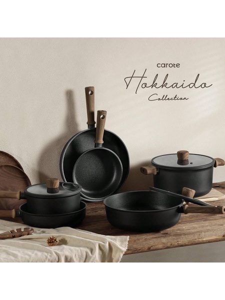 This ad creative displays a complete set of black cookware with wood-accented handles arranged in a clean, minimalist kitchen setting.