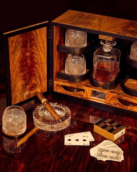 A high-end, cinematic product display featuring a whiskey decanter set, crystal glasses, and cigars on a polished wooden surface, evoking a premium lifestyle.