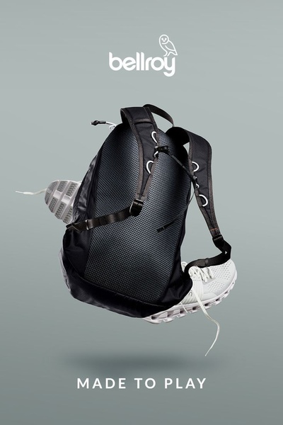 A high-contrast, clean studio shot of a black backpack appearing to float with footwear, set against a neutral gray background.