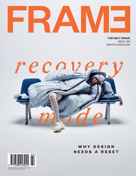 A striking studio shot of a model wearing a light blue oversized puffer coat while resting on a bench, featuring glitch-style pixelated typography.