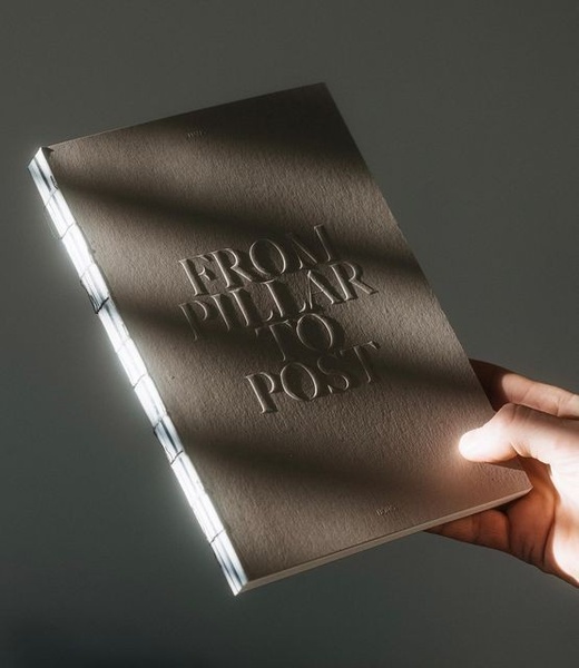 A high-end product photography shot of a hardcover book held in a hand, featuring dramatic, soft directional lighting that emphasizes the embossed title.