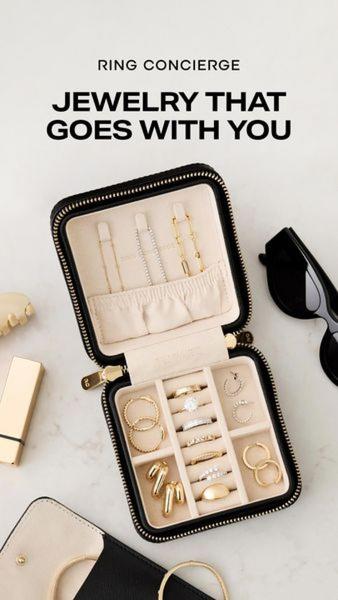 A high-end flat lay shot of a compact travel jewelry case open on a marble surface, displaying organized pieces alongside daily essentials.