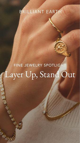 A close-up lifestyle shot of a hand wearing stacked gold rings and bracelets, demonstrating a minimalist and elegant styling approach.
