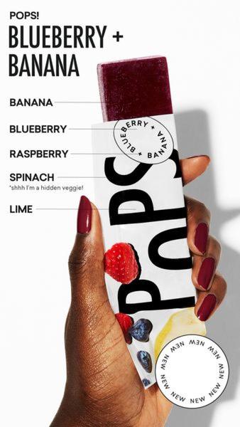 A close-up vertical shot featuring a hand holding a popsicle with overlaid text lines pointing to each specific fruit and vegetable ingredient inside.