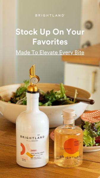 A lifestyle-focused product shot showcasing high-end olive oil and vinegar bottles beside a fresh salad, emphasizing premium quality.