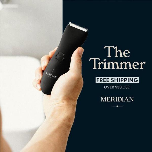 A high-contrast 1:1 image featuring a hand holding a black body trimmer against a dark, professional background.
