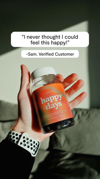 A close-up shot of a hand holding a bottle of 'Happy Days' gummies against a soft, natural background, featuring a strong emotional testimonial quote.
