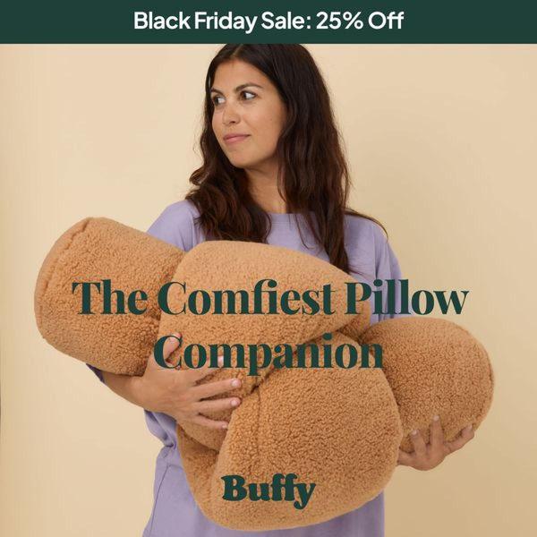 A clean, minimalist lifestyle shot featuring a model holding a plush brown pillow. The ad uses a simple color palette and text overlay to emphasize comfort during a sale.