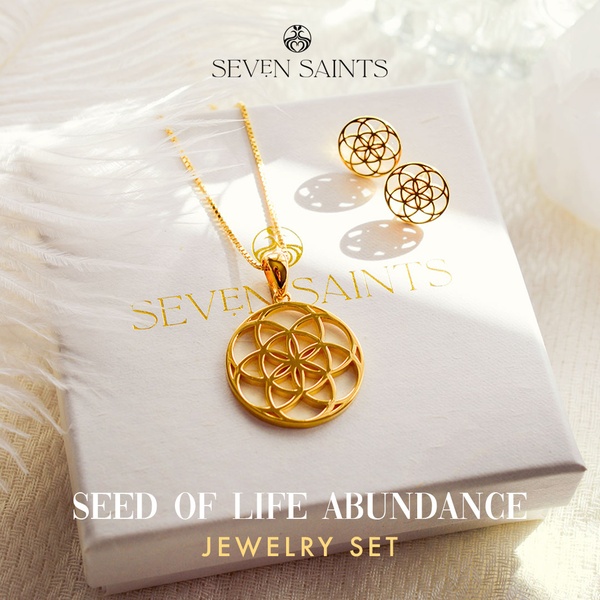 A close-up photograph featuring a gold necklace and earring set resting on a premium jewelry box under natural lighting.