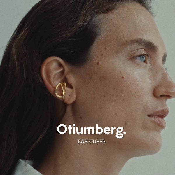 A close-up side profile shot of a model wearing a singular, organic gold ear cuff against a neutral background.