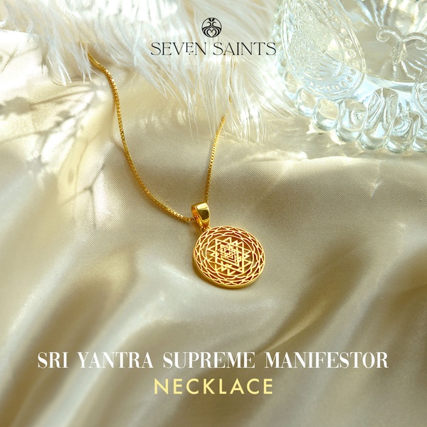 A refined product hero shot featuring a gold Sri Yantra necklace resting on soft, flowing fabric to evoke luxury and spiritual significance.