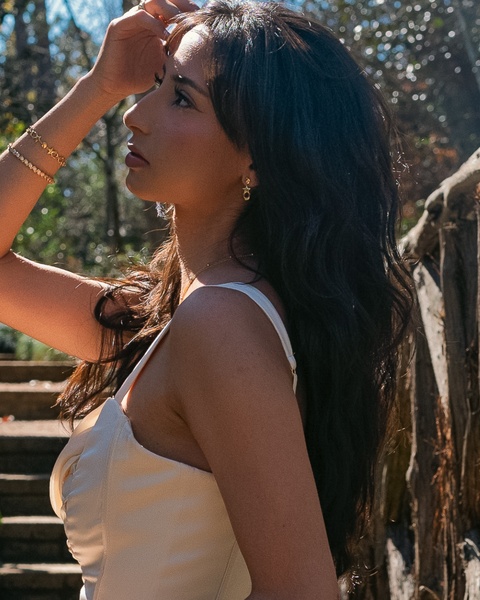 A close-up, sun-drenched portrait shot of a model wearing minimalist jewelry, focusing on soft lighting and natural aesthetic.