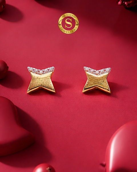 A close-up studio shot of star-shaped gold stud earrings with delicate crystal detailing, set against a rich, festive red background.