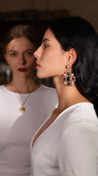 A refined, high-fashion profile shot featuring a model wearing statement cross earrings, emphasizing premium design and minimalist aesthetic.