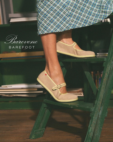 A high-end lifestyle shot of Mary Jane flats, showcasing the product in a natural, cozy library environment to emphasize comfort and style.