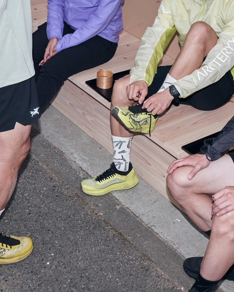 A close-up, high-angle shot focusing on a group of athletes resting and adjusting their performance footwear in a shared, candid environment.