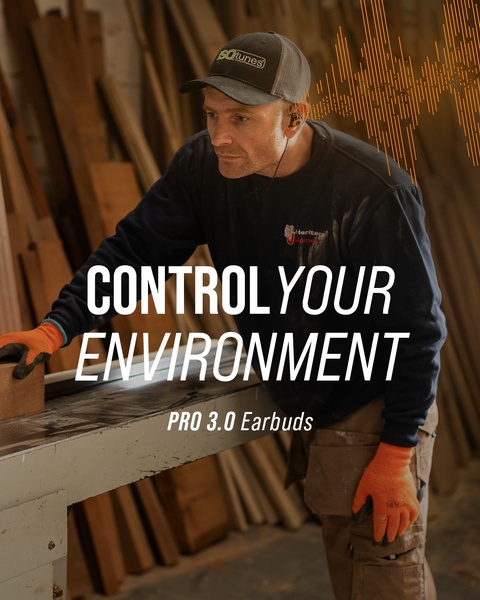 A focused shot of a professional in a woodshop using safety-focused earbuds, highlighting the product benefit of noise-controlled work environments.