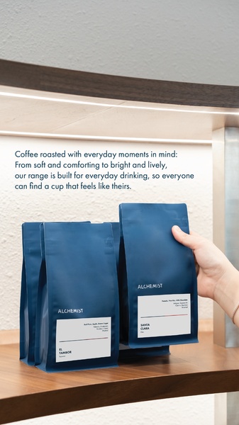 A close-up studio shot showing a hand reaching for premium coffee bags on a shelf, conveying ease and accessibility through clean, warm lighting.