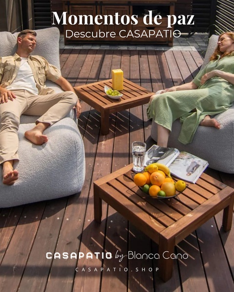A high-quality lifestyle shot featuring a couple relaxing on comfortable bean bag chairs on a wooden patio deck with fresh fruit.