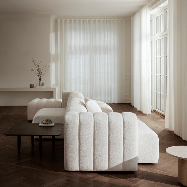 A high-end editorial shot of a textured linen sofa in a bright, airy living room space with neutral tones.