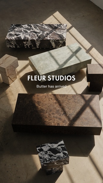 A high-angle, naturally lit composition showcasing various stone coffee table designs from a minimalist collection.