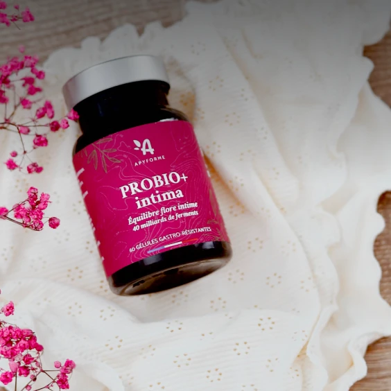 A high-quality 1:1 product shot of a probiotic supplement bottle placed on a delicate, textured white cloth with vibrant pink flowers.