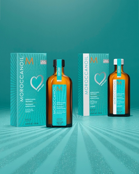 A clean, symmetrical product display featuring two hair oil bottles against a vibrant turquoise background with subtle radial lighting.