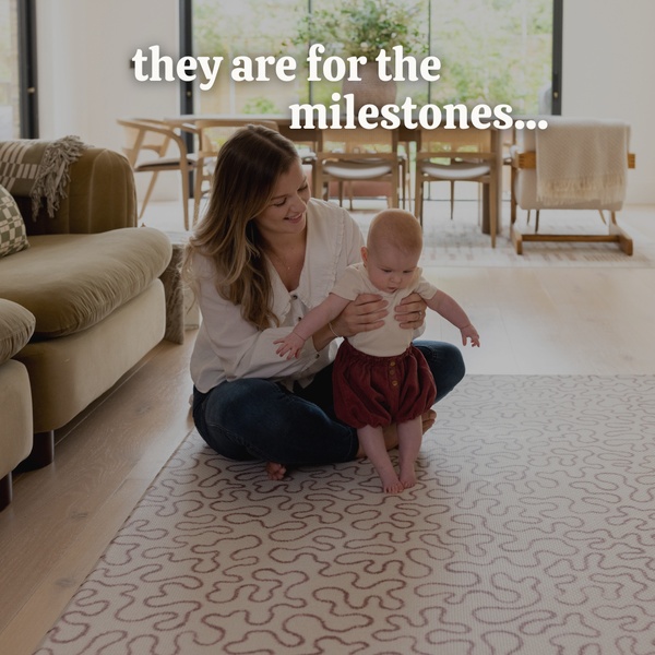 A lifestyle-focused ad creative showing a mother and baby on a patterned area rug with text overlay highlighting emotional milestones.