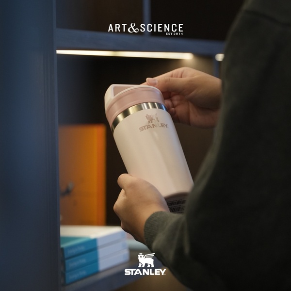 A close-up shot showing a person holding and inspecting a pastel Stanley tumbler, focusing on the product's quality and aesthetic.