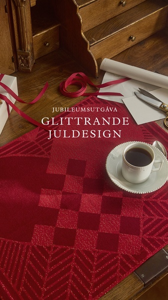 A high-angle, elegant tabletop scene featuring a glitter-textured red Christmas-themed table cloth, a white ceramic coffee cup, and stationery tools.