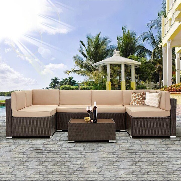 A high-quality 1:1 image showcasing a modular wicker patio sofa set on a stone patio during a sunny afternoon.
