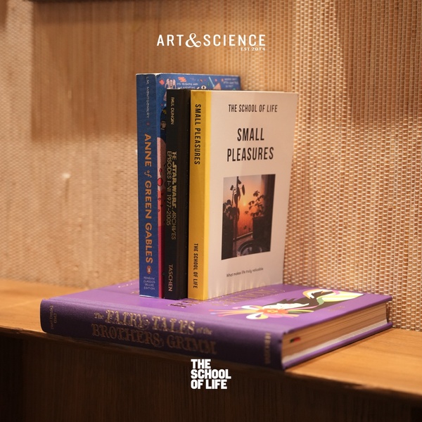 A high-quality, static image featuring a stack of carefully curated books on a wooden surface, set against a neutral, textured wall.