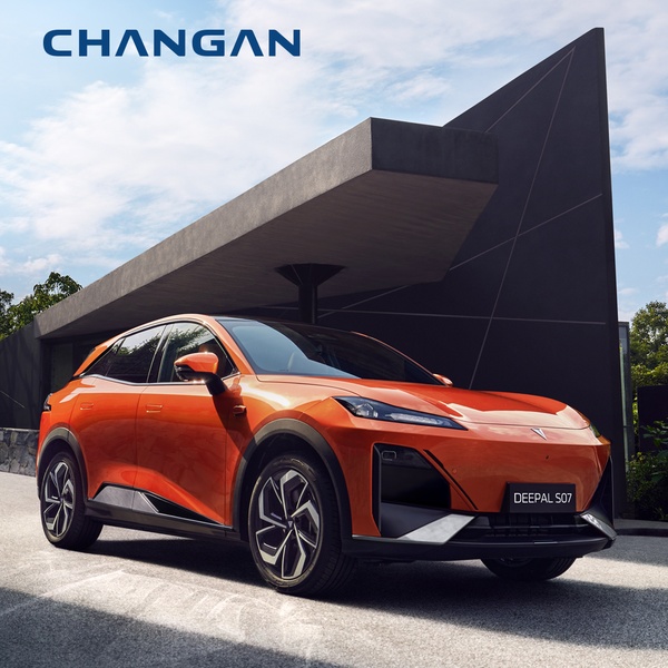 An orange electric SUV positioned in front of a sharp, minimalist modern structure, emphasizing luxury design and clean lines.