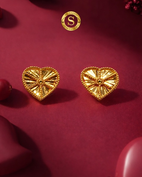 A close-up product shot of a pair of gold, heart-shaped textured earrings set against a deep burgundy background with a premium brand logo.