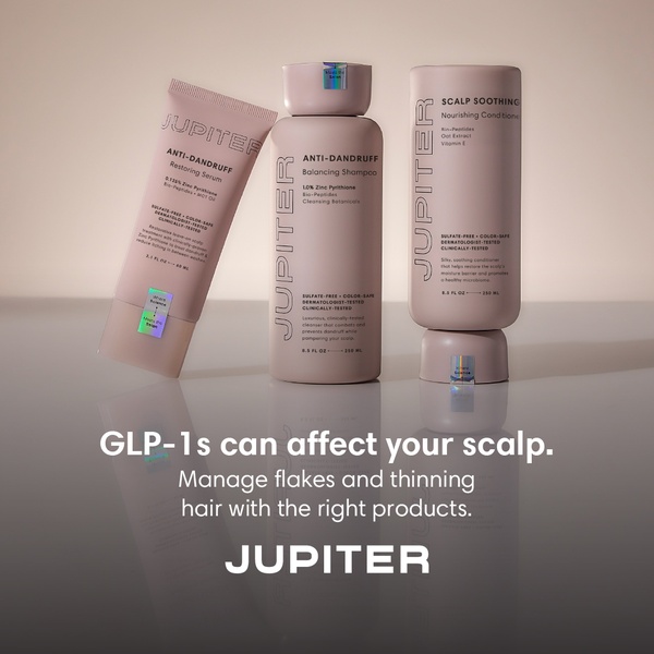 A clean, minimalist product shot featuring a scalp-care serum, shampoo, and conditioner set against a neutral, calming background.