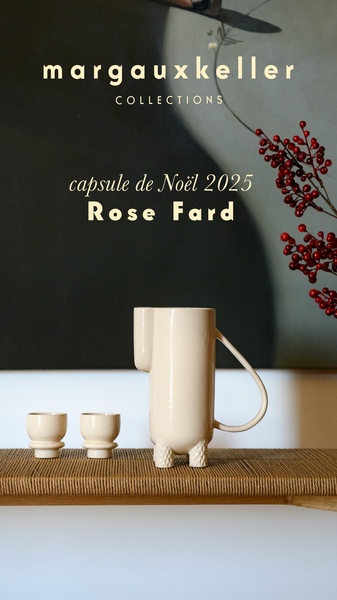 A high-end, minimalist presentation of a ceramic pitcher and matching cups, framed against a dark, moody backdrop with festive red berries.