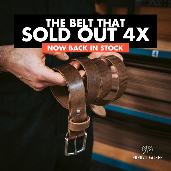 A close-up product shot of a leather belt being held by a craftsman, featuring a bold text overlay highlighting a successful restock.