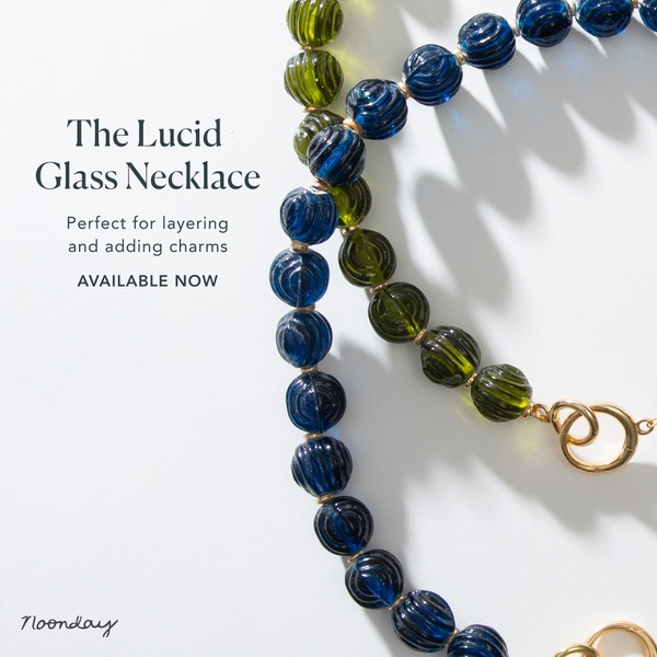 A close-up, high-contrast shot of a glass bead necklace on a clean white background, highlighting its design and layering potential.