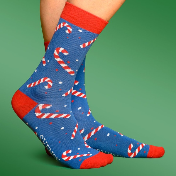 A close-up studio shot showing patterned socks with a candy cane design against a solid green background.