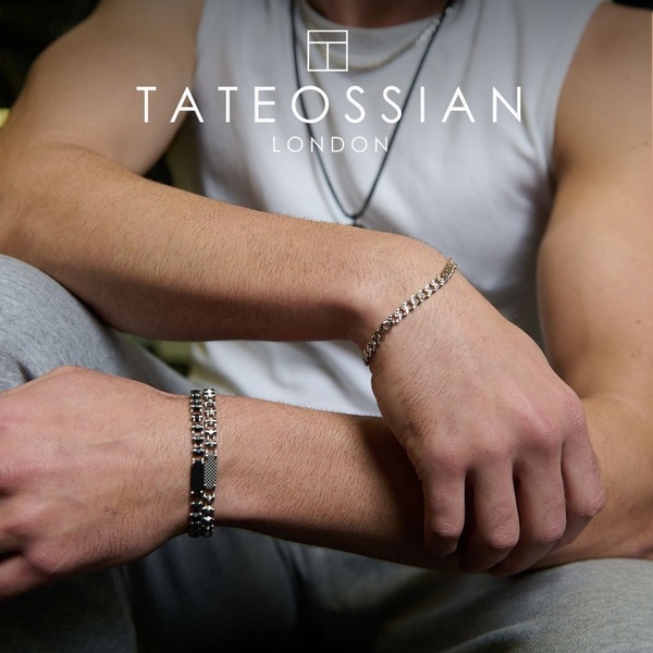 A close-up, high-contrast lifestyle image showcasing a man wearing two different metal bracelets, emphasizing the product's design details and premium aesthetic.
