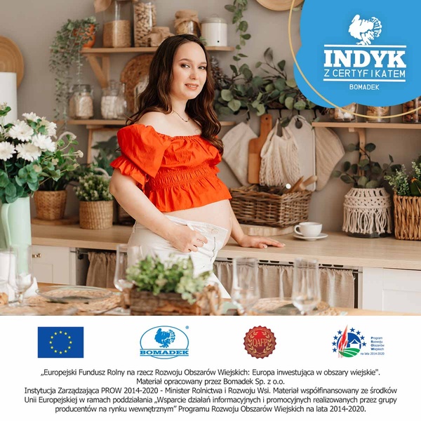 A natural, warm-toned lifestyle shot of a pregnant woman in a rustic kitchen environment representing a food brand.