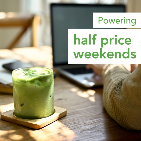 A clean, lifestyle-oriented image showing a glass of iced matcha on a wooden table with a laptop in the background, promoting a half-price weekend deal.
