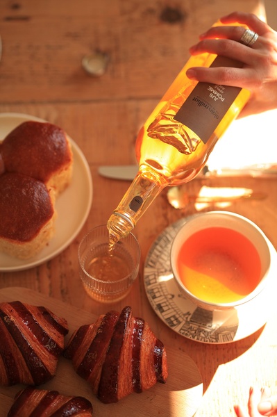 A high-quality lifestyle shot showing apple juice being poured into a glass, surrounded by pastries on a wooden table.