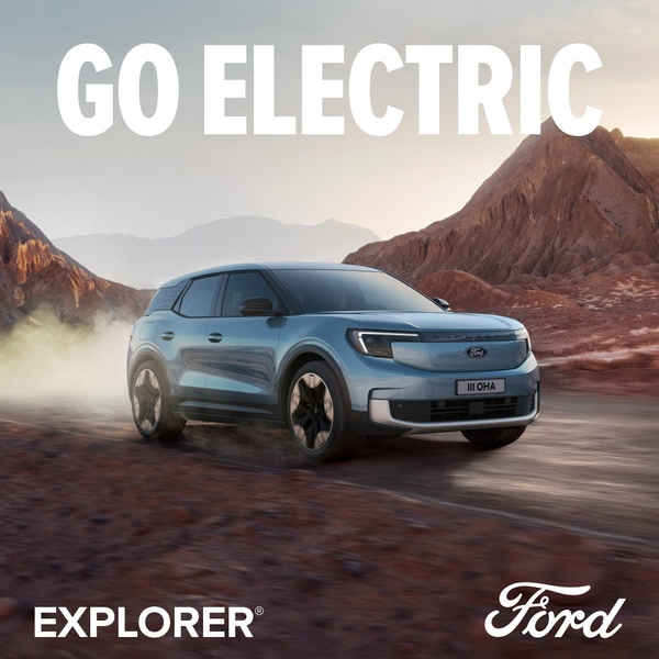 A high-quality lifestyle shot featuring an electric SUV driving through a rugged, desert-like landscape, highlighting adventure and performance.