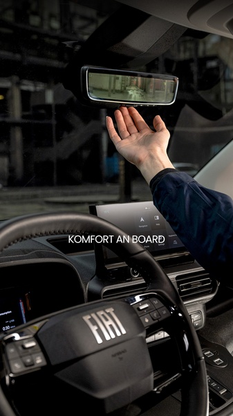 A close-up shot showing a driver's hand reaching for a smart rearview mirror inside a vehicle, highlighting modern comfort and visibility features.