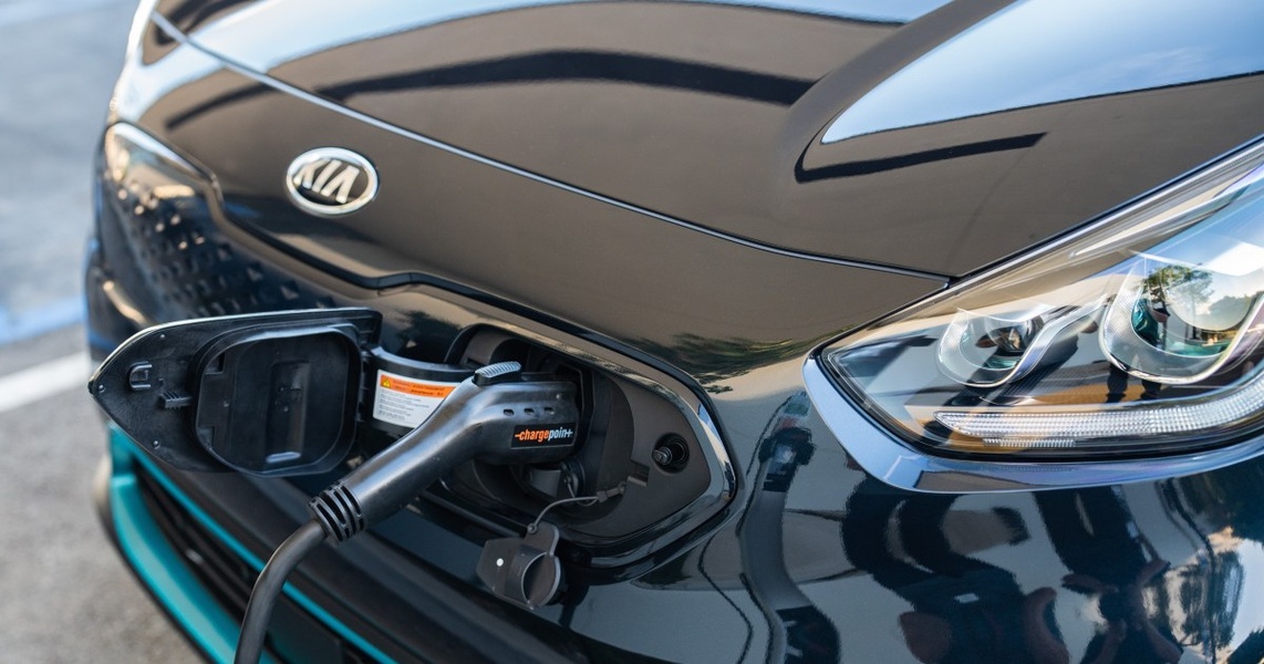 A high-fidelity hero shot showing an electric vehicle being charged with a ChargePoint unit, focusing on the plug interface and sleek car design.