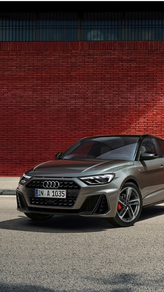 A high-fidelity studio-style hero shot of an Audi A1 parked against a textured brick wall, emphasizing the vehicle's design and color.